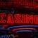 Neon lights display the word 'CASINO' in bright red, standing out against a dark background. The vibrant glow reflects a lively and bustling atmosphere.